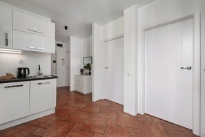 Eine moderne Küche mit weißen Schränken, einer schwarzen Arbeitsplatte und einem gefliesten Boden.