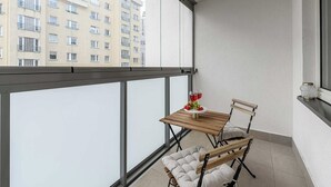 A balcony with a table and chairs, a glass of red wine, and a fruit bowl.