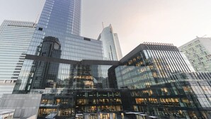A modern glass building with a curved facade, surrounded by other high-rise structures. - Modern Apartment Stay Near Paris (Warszawa)