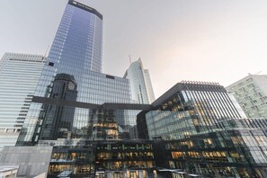 Ein modernes Glasgebäude mit einer gewölbten Fassade, umgeben von weiteren Hochhäusern.