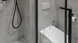 A modern bathroom with a toilet, a shower, and a towel rack. - Modern Apartment Stay Near Paris (Warszawa)