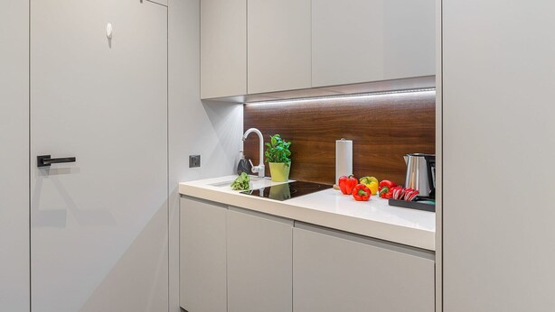 A modern kitchen with a built-in stove, a sink, and a wooden backsplash. - Modern Apartment Stay Near Paris (Warszawa)