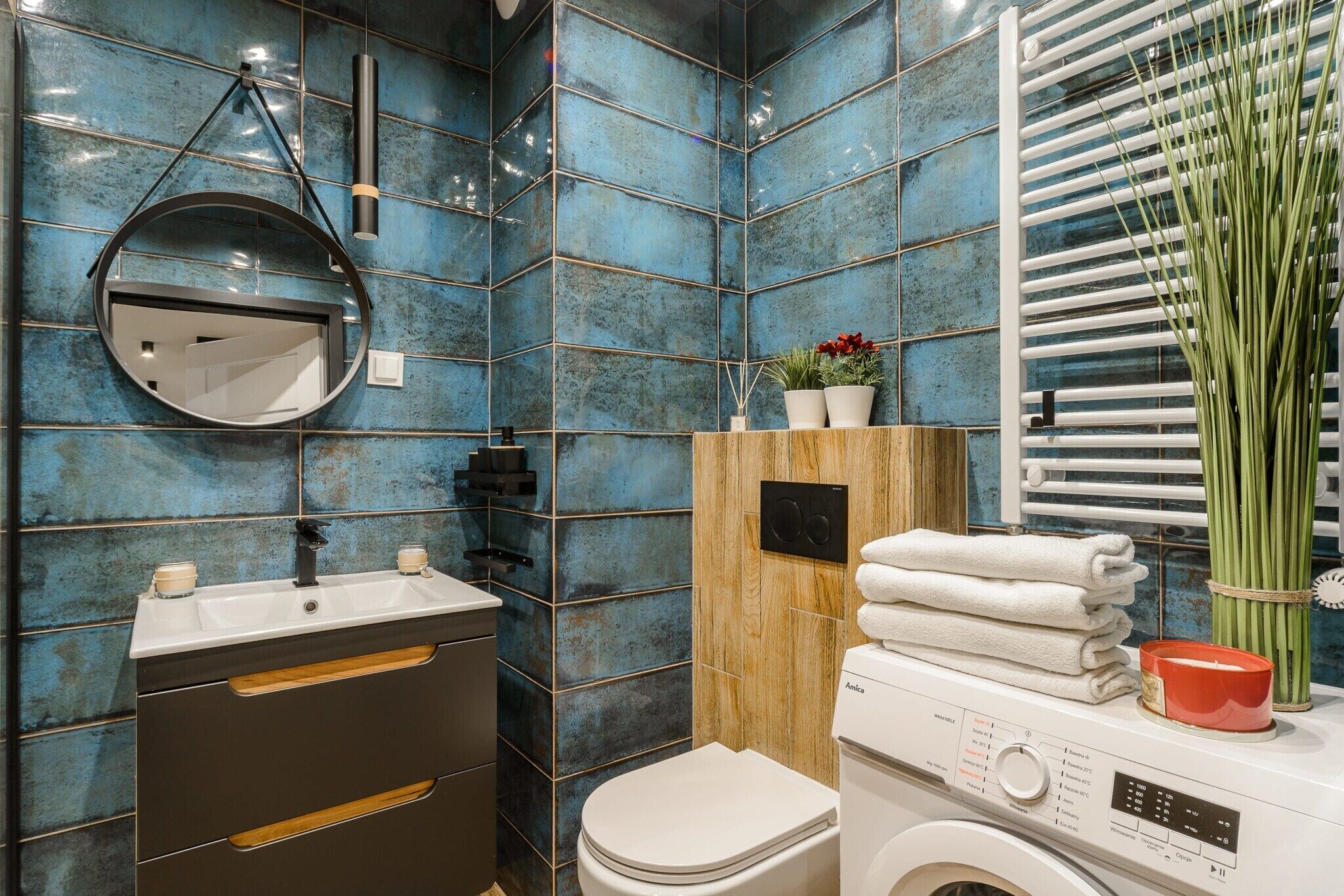 A modern bathroom with a sink, mirror, toilet, and washing machine.
