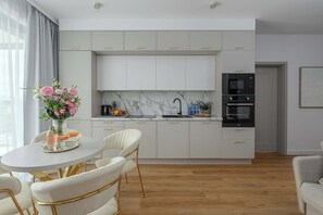 Eine moderne Küche mit weißen Schränken, einer Marmorarbeitsplatte und einem eingebauten Backofen.
