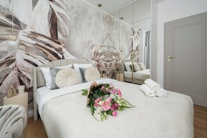A modern bedroom with a large bed, a mirror, and a floral wall mural. - Family home steps from the beach (Warszawa 2)