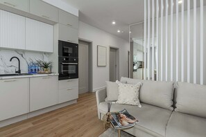 A modern kitchen with white cabinets, a black oven, and a marble countertop. - Family Apartment with Balcony in Warsaw (Warszawa 2)
