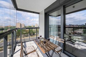 A balcony with a table, chairs, and wine glasses, overlooking a cityscape. - Family home steps from the beach (Warszawa 2)