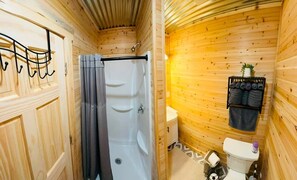 A wooden cabin bathroom with a bathtub, toilet, and a towel rack. - Cozy 2-bedroom cabin in beautiful McLeod with AC (McLeod)