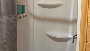 Een douche met houten plafond, douchegordijn en handdouche.