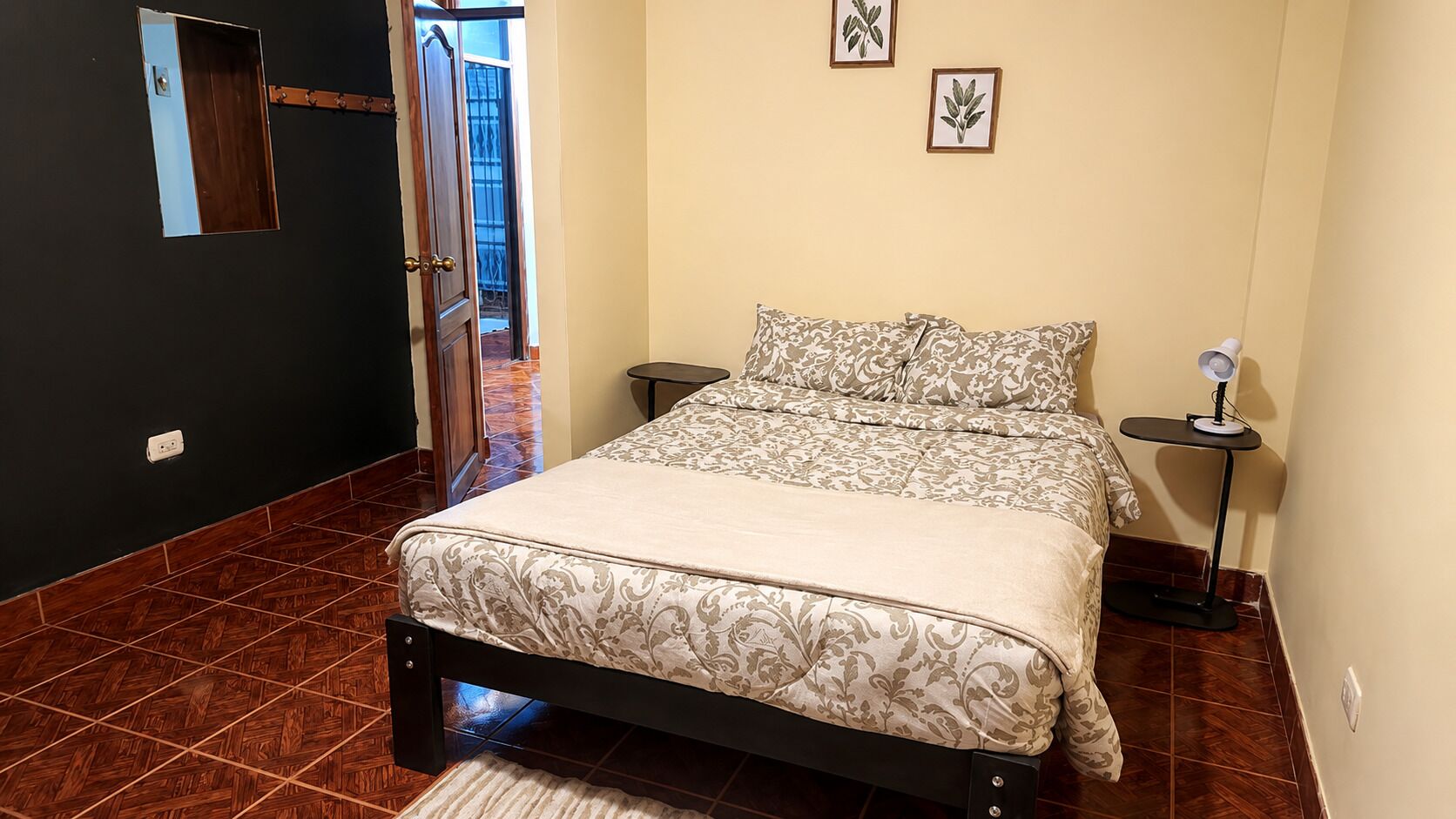 Une chambre à coucher comprenant un lit, des tables de chevet, un miroir et une porte donnant sur un balcon.