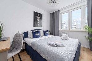 Une chambre moderne avec un lit, un bureau, une chaise, un radiateur et une fenêtre donnant sur un beau paysage.