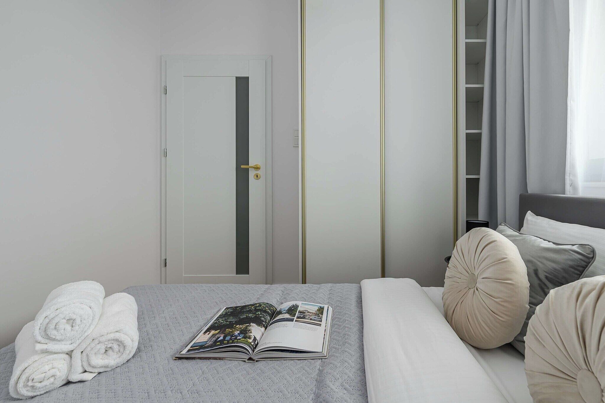 Een hotelkamer met een bed, een kledingkast, een deur en een raam met gordijnen.