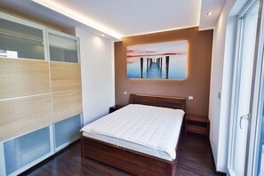 Une chambre moderne avec un lit en bois, une armoire intégrée et une grande fenêtre.