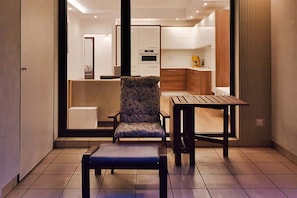 A compact living space with a kitchenette, a dining area with a table and chair, and a seating area with a patterned chair. - City Apartment for 6 guests (Warszawa)