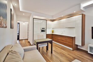 Une cuisine moderne avec des meubles blancs, un plan de travail en bois et un four encastré.