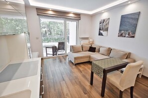 A modern living room with a sofa, a dining table, and a view to the outside. - City Apartment for 6 guests (Warszawa)