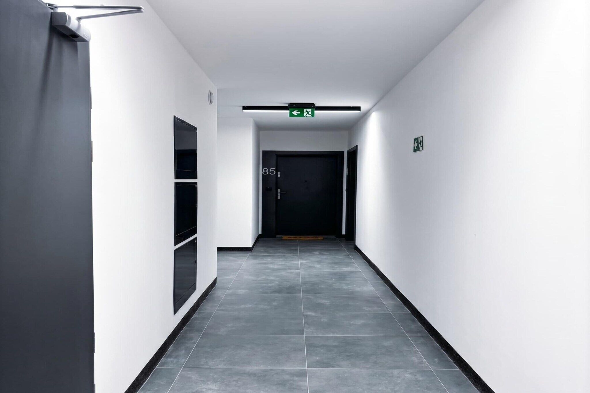 A hallway with a door marked '85' and an exit sign above it.
