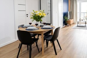 A dining area with a round table, black chairs, and a vase of yellow flowers. - Pretty House by the Sea for 4 (Łódź)