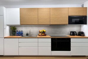 A modern kitchen with white cabinetry, a wooden countertop, a black microwave, and a fruit basket. - Pretty House by the Sea for 4 (Łódź)