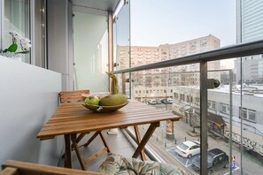 Ein Balkon mit Holztisch, Obstschale und Stuhl.