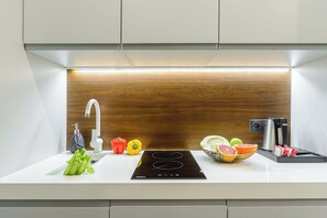 A modern kitchen with a white countertop, a built-in sink, a stainless steel faucet, a black induction cooktop, and a coffee maker. - Plouguerneau Coastal Retreat with Garden (Warszawa)