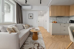 A modern living room with a sofa, coffee table, and a view into the kitchen. - House in Saint-Pabu near Stunning Beaches (Warszawa 2)