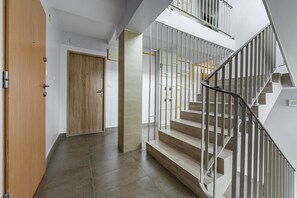 A modern interior with a wooden door, a staircase with metal railings, and a tiled floor. - House in Saint-Pabu near Stunning Beaches (Warszawa 2)
