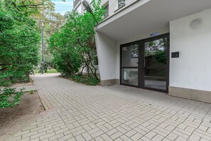 A paved pathway leading to a building entrance with a glass door and a sign above it. - Elegant Family Apartment in Nowolipki (Warszawa 2)