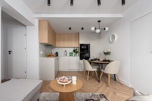 A compact living space with a kitchenette, dining area, and a bed. - Elegant Family Apartment in Nowolipki (Warszawa 2)