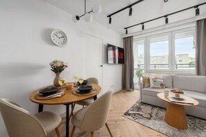 Un salon moderne comprenant un coin repas, un canapé, une table basse, un téléviseur et une horloge murale.