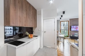 Een moderne keuken met witte kasten, een houten bovenkast en een ingebouwde kookplaat.