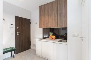 Eine moderne Küche mit weißen Schränken, einer Holztür und einer kleinen Bank.
