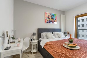 A modern hotel room with a large bed, a desk, and a window with a city view. - City Apartment with Balcony (Warszawa)