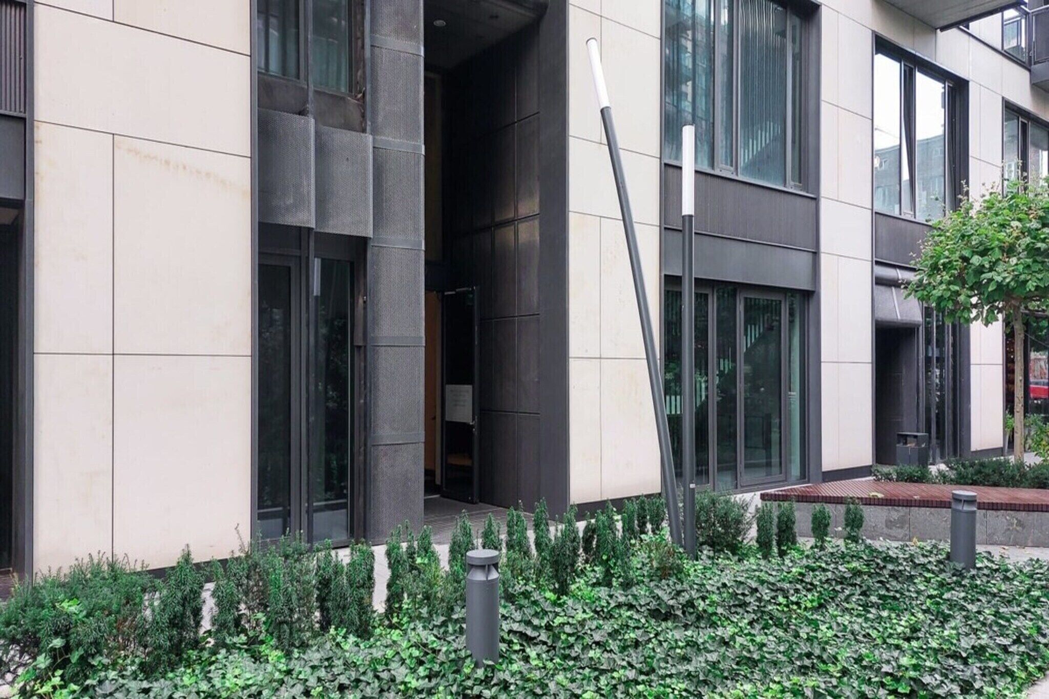 A modern building with large windows and a landscaped garden area.