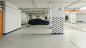 A parking garage with a blue car parked in a designated space marked with the number 103. - City Apartment with Balcony (Warszawa)