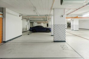 A parking garage with a blue car parked in a designated space marked with the number 103. - City Apartment with Balcony (Warszawa)
