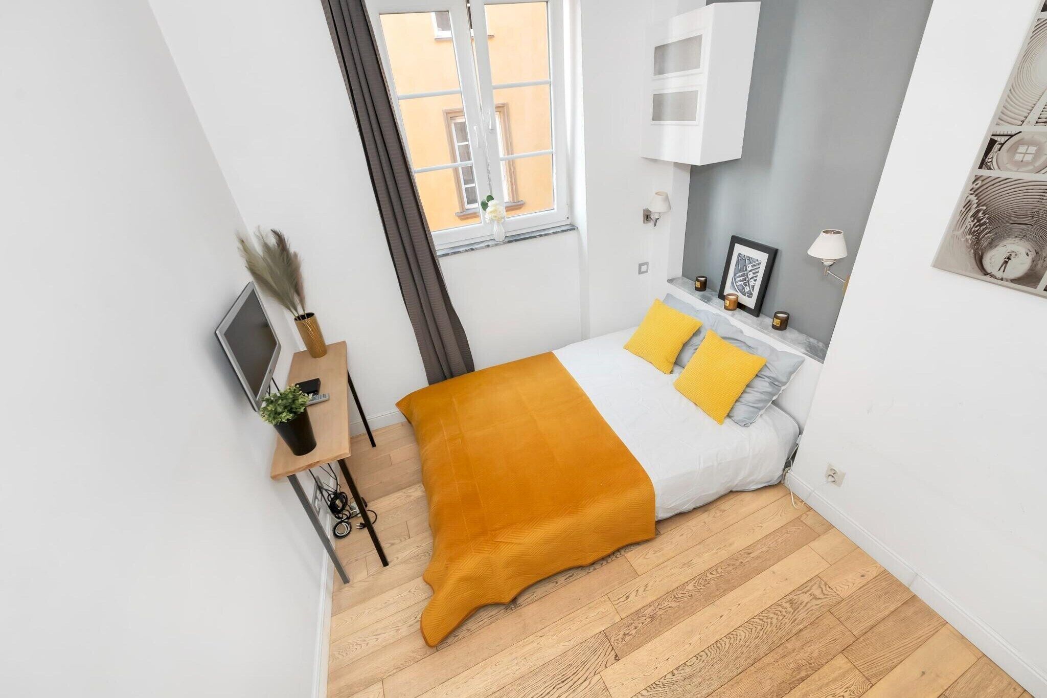 A modern bedroom with a bed, bedside table, lamp, and a view of the outside.