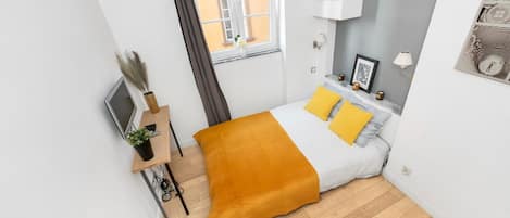 Une chambre à coucher moderne, avec un lit, une table de chevet, une lampe et une vue sur l’extérieur.