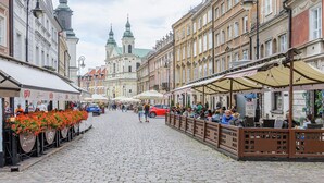 A cobblestone street lined with historic buildings, outdoor cafes, and flower arrangements. - Comfortable house with splendid sea view (Warszawa)