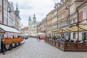 Eine Kopfsteinpflasterstraße gesäumt von historischen Gebäuden, Straßencafés und Blumenarrangements.