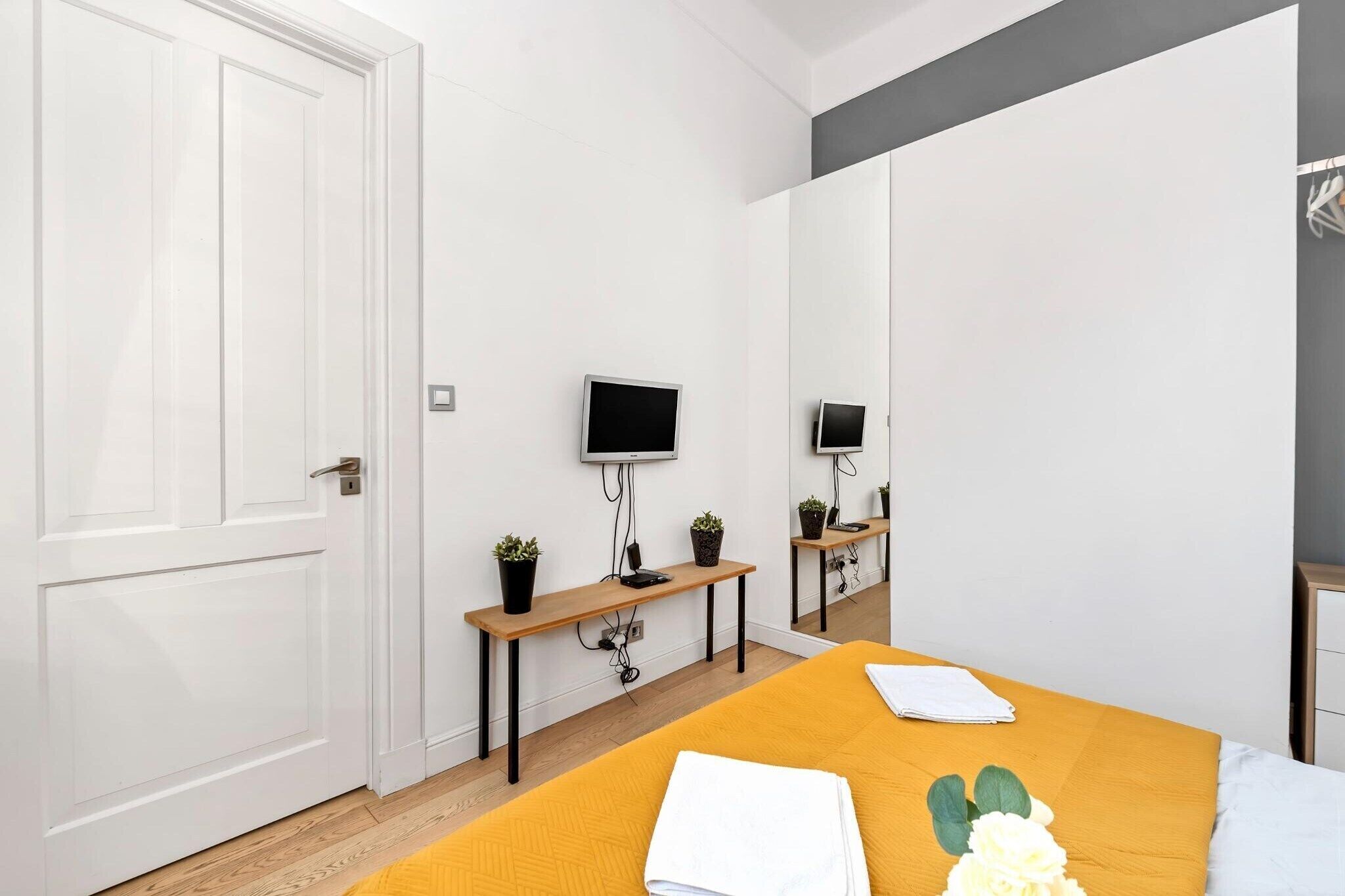 Une chambre à coucher avec un lit, un bureau, une télévision et un miroir.