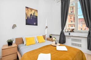 Ein modernes Schlafzimmer mit einem Bett, Nachttischen, einem Fenster mit Vorhängen und einem Stadtbild an der Wand.