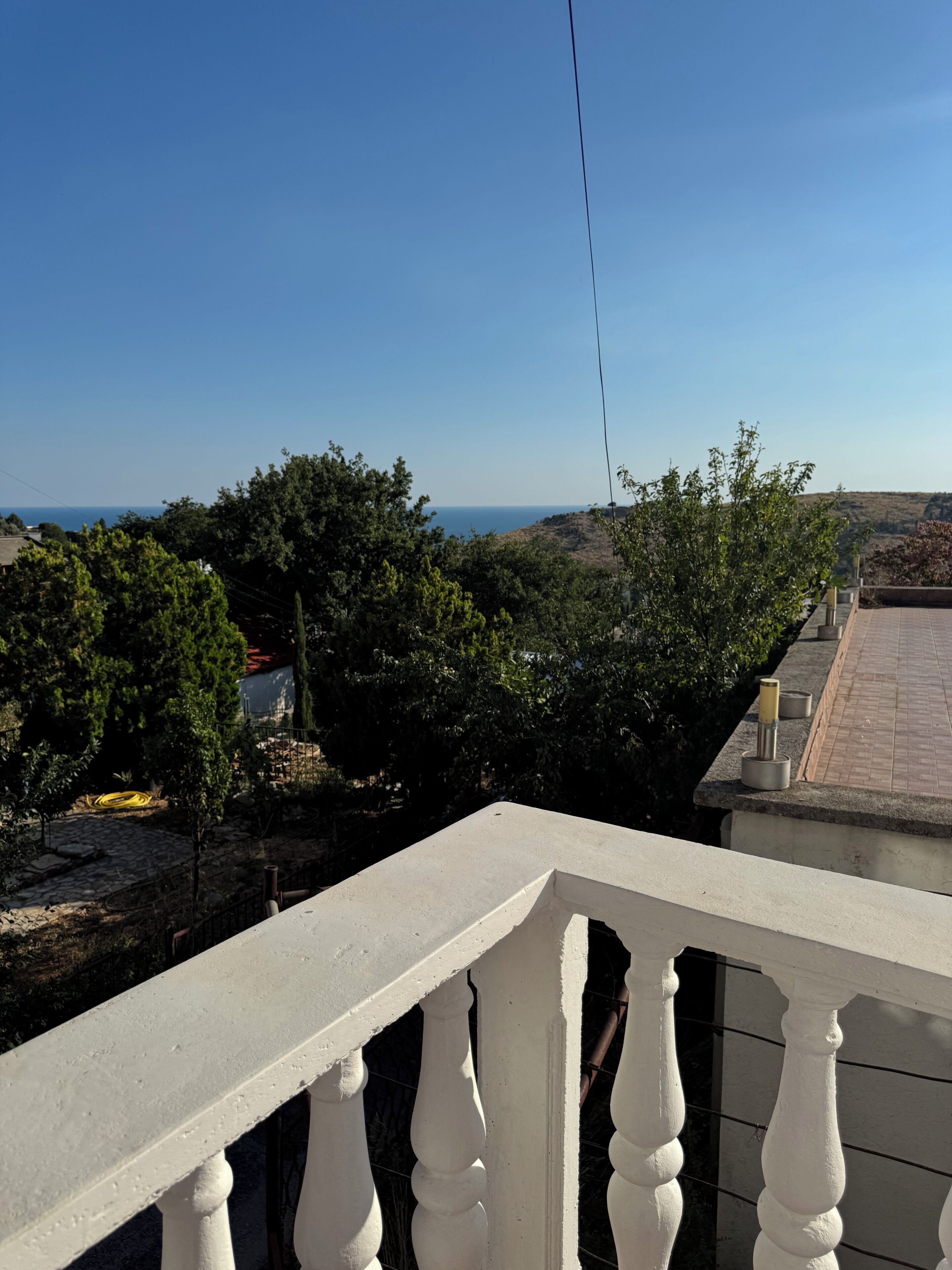 Un balcón con vista despejada al mar y al follaje circundante.