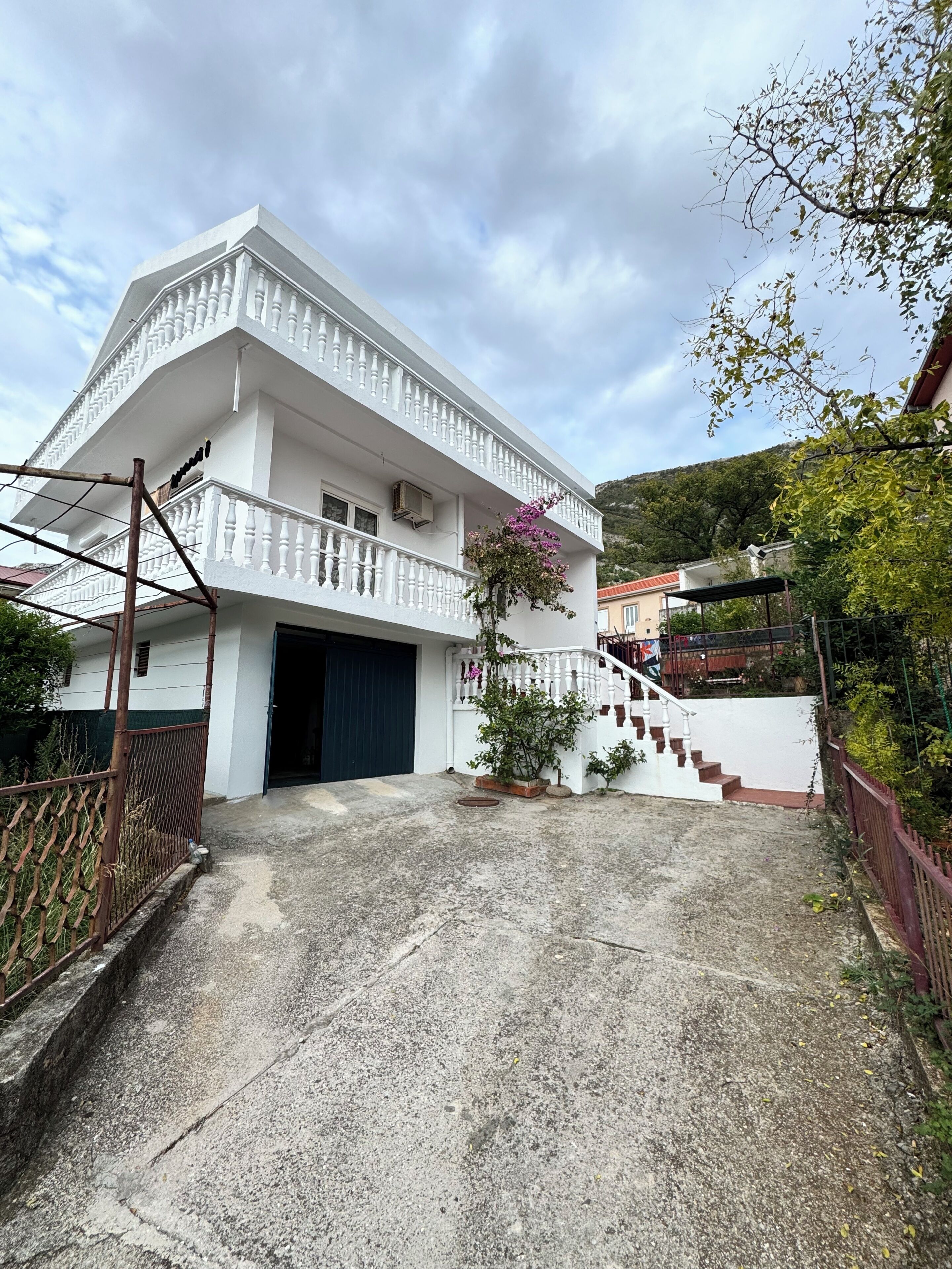 Un bâtiment blanc doté d’un balcon, d’un escalier et d’un espace jardin.
