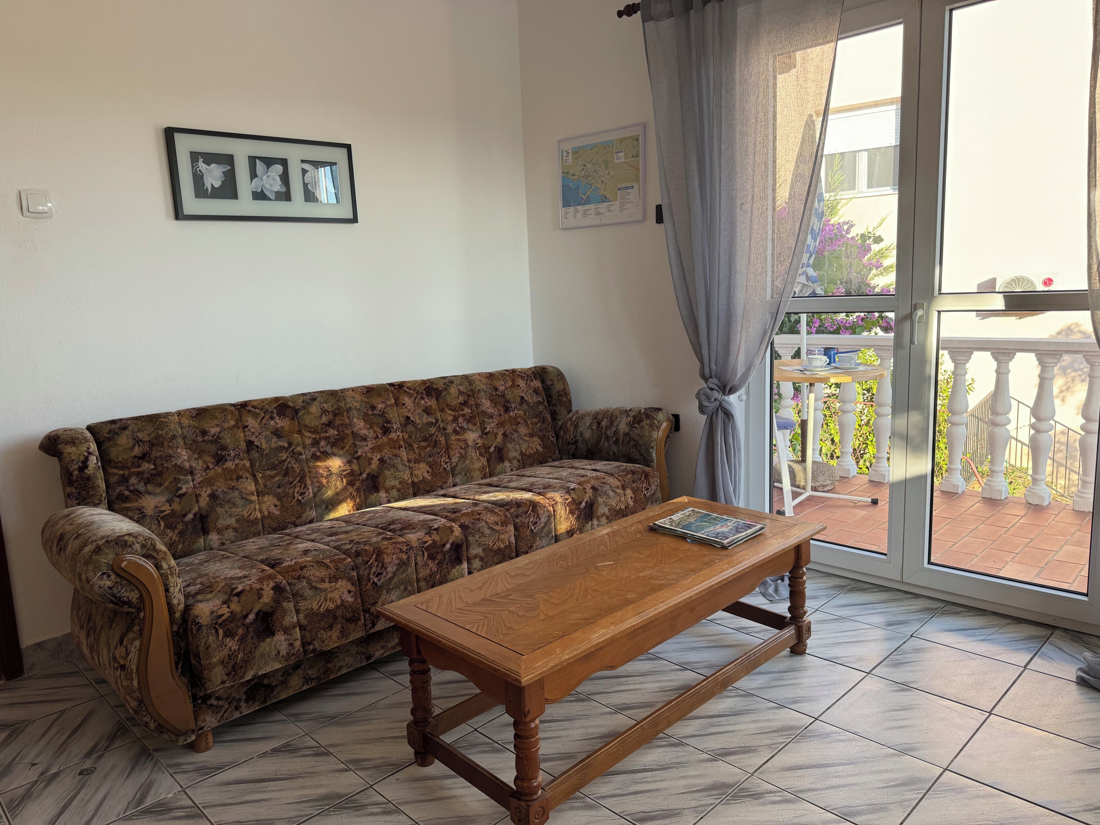 Una sala de estar con un sofá, una mesa de centro de madera y vistas al exterior a través de un ventanal.