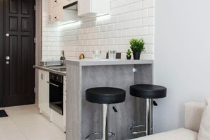 Eine moderne Küche mit Barbereich, zwei Barhocker und einem Blumentopf.