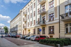 Eine Reihe von mehrstöckigen Wohngebäuden mit Balkonen, einem Parkschild und geparkten Autos.