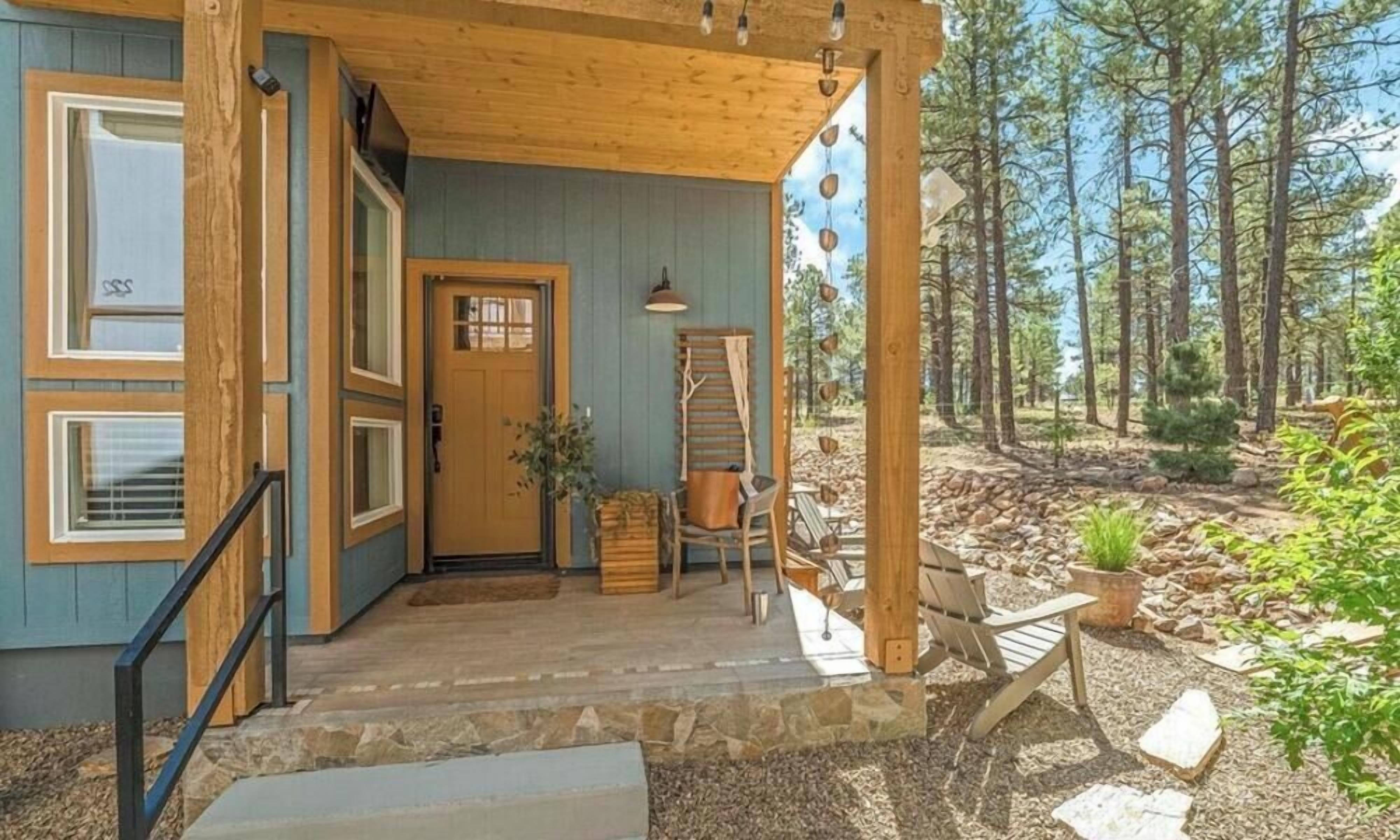 A wooden cabin with a porch, a door, and a window.