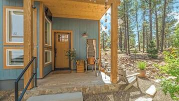 A wooden cabin with a porch, a door, and a window.