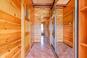 Ein Innenbereich mit Holzboden, gefliestem Fußboden, Türen und einer Glastrennwand.